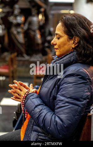 Femme priant dans l'église catholique notre Dame du Finisterre, Bruxelles, Belgique. Banque D'Images