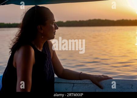 Femme sur un bateau naviguant dans le delta du fleuve Saloum au crépuscule, Sénégal Banque D'Images