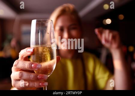 Jeune femme élégante portant une robe jaune buvant une coupe de champagne dans un bar lounge d'hôtel cinq étoiles. Bangkok. Thaïlande. Banque D'Images