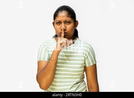 Une femme mettant son doigt dans son geste de bouche sur un fond blanc. Banque D'Images