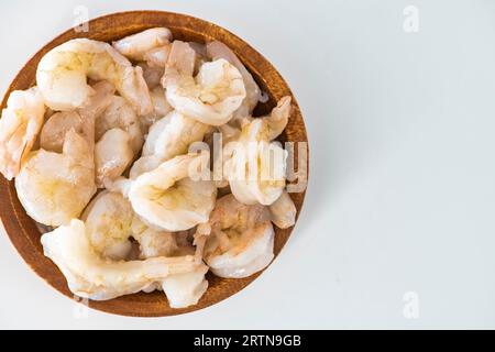 Crevettes crues fraîches nettoyées et conservées dans un bol en bois. Crevettes crues dans un bol en bois et isolées en fond blanc. Banque D'Images