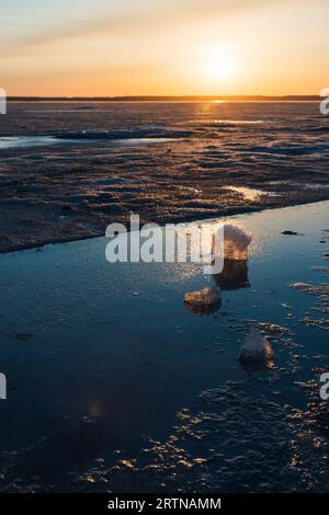 Paysage d'hiver avec lac gelé. Les glaçons reposent au soleil sur un coucher de soleil, photo verticale rapprochée Banque D'Images