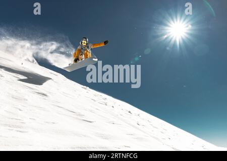 Vrai jeune snowboarder saute et fait tour de kicker à la piste de ski hors piste. Concept de vacances d'hiver Banque D'Images