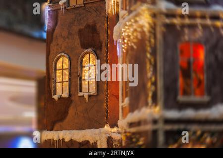 Arrière-plan pour la conception. Décorations du nouvel an, jouets et guirlandes sur les fenêtres dans des paysages fabuleux. Maisons pour enfants dans un lieu public. Banque D'Images