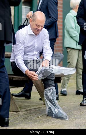 Brême, Allemagne. 14 septembre 2023. Le chancelier allemand OLAF Scholz (SPD) met des surbottes avant de visiter un hangar à vaches dans la ferme biologique de la famille Sündermann. Le chancelier a examiné la culture laitière dans la ferme de la famille Sündermann à Brême-Oberneuland. Crédit : Hauke-Christian Dittrich/Pool/dpa/Alamy Live News Banque D'Images