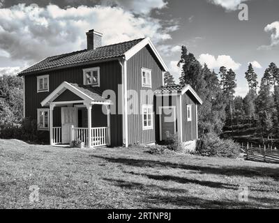 Une maison typique de Suède rouge et blanc dans smalland en noir et blanc. Dans le ciel avec de petits nuages. Photo de paysage de Scandinavie Banque D'Images