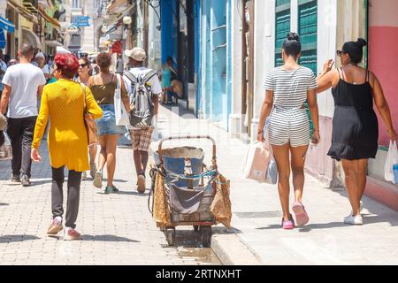 La Havane, Cuba - 30 août 2023 : les gens marchent devant un chariot rustique d'une balayeuse de rue. Banque D'Images