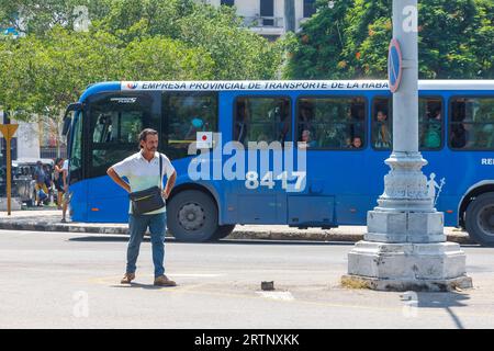 La Havane, Cuba - 30 août 2023 : un cubain se tient au coin du Parque Central. Un bus public roule en arrière-plan. Banque D'Images