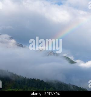 Un arc-en-ciel au-dessus d'un sommet de montagne enveloppé de nuages dans le parc national du Triglav en Slovénie Banque D'Images