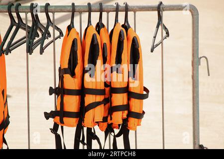 Les gilets de sauvetage sont accrochés à des cintres dans la rue sous le soleil d'été près de la rivière Banque D'Images