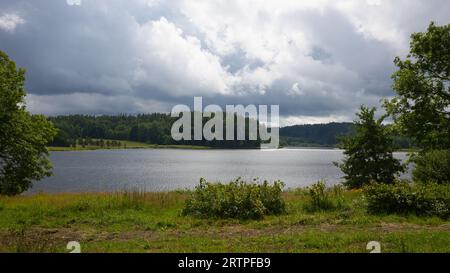 Des nuages sombres surplombent un lac au bord de la forêt sur l'île d'Orust en Suède. Banque D'Images