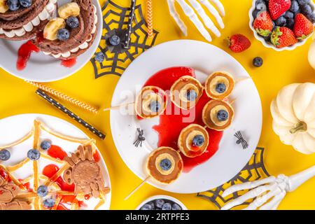 Petit déjeuner drôle pour les enfants pour Halloween. Crêpes sucrées maison créatives sous forme de monstres et symboles traditionnels d'Halloween, avec baies fraîches, chocolat Banque D'Images