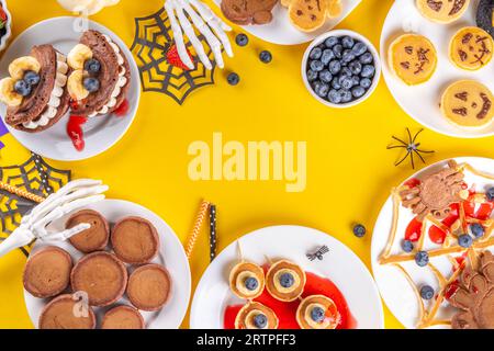 Petit déjeuner drôle pour les enfants pour Halloween. Crêpes sucrées maison créatives sous forme de monstres et symboles traditionnels d'Halloween, avec baies fraîches, chocolat Banque D'Images