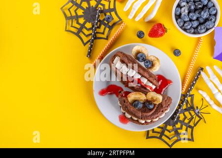 Petit déjeuner drôle pour les enfants pour Halloween. Crêpes sucrées maison créatives sous forme de monstres et symboles traditionnels d'Halloween, avec baies fraîches, chocolat Banque D'Images