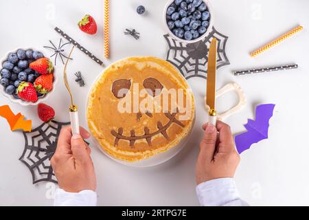 Petit déjeuner drôle pour les enfants pour Halloween. Crêpes sucrées maison créatives sous forme de monstres et symboles traditionnels d'Halloween, avec baies fraîches, chocolat Banque D'Images