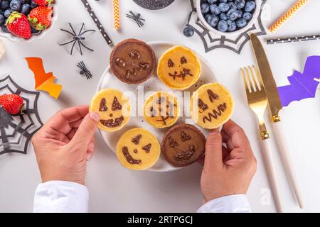 Petit déjeuner drôle pour les enfants pour Halloween. Crêpes sucrées maison créatives sous forme de monstres et symboles traditionnels d'Halloween, avec baies fraîches, chocolat Banque D'Images