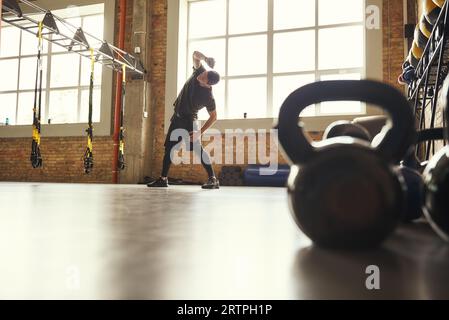Échauffement avant l'entraînement. Jeune homme sportif en vêtements de sport faisant des exercices d'étirement tout en se tenant devant la fenêtre à la salle de gym Banque D'Images