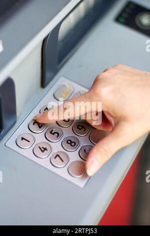 Main de personne anonyme mettant le numéro secret dans le guichet automatique de la banque pour s'identifier et être en mesure de retirer de l'argent. Banque D'Images