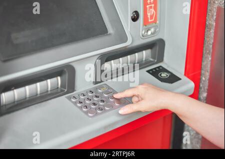Main de personne anonyme mettant le numéro secret dans le guichet automatique de la banque pour s'identifier et être en mesure de retirer de l'argent. Banque D'Images