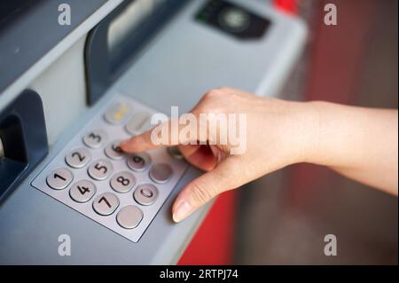 Main de personne anonyme mettant le numéro secret dans le guichet automatique de la banque pour s'identifier et être en mesure de retirer de l'argent. Banque D'Images