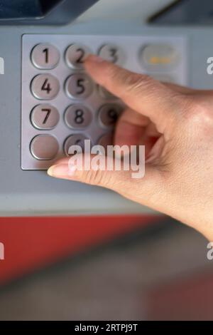 Main de personne anonyme mettant le numéro secret dans le guichet automatique de la banque pour s'identifier et être en mesure de retirer de l'argent. Banque D'Images