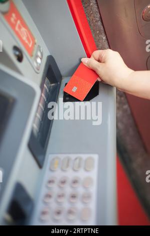 Main de femme méconnaissable utilisant votre carte de crédit à un distributeur automatique de billets dans la mise au point sélective. Banque D'Images