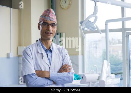 Katmandou, Népal - 02 septembre 2023 : dentiste népalais confiant avec topi ou chapeau traditionnel népalais dhaka et robe de médecin Banque D'Images