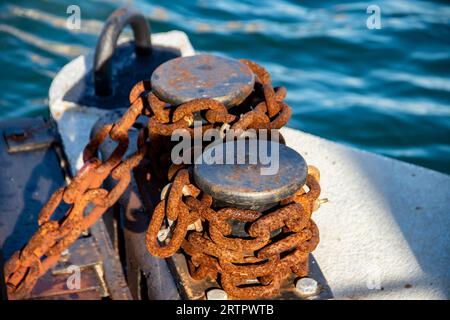 Vieille chaîne d'ancre abandonnée avec de la rouille et des taquets de fer, hawser sur un poteau dans un quai local en Italie Banque D'Images