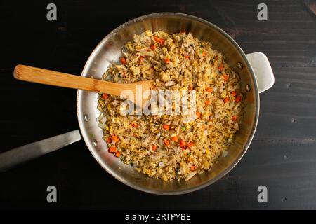 Riz frit au crabe de style thaïlandais dans une grande poêle avec une spatule en bambou : une poêle remplie de riz frit aux fruits de mer fraîchement préparés vue de dessus Banque D'Images