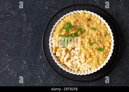 mac cuit au four et fromage saupoudré de chapelure panko et de persil frais dans un plat allant au four sur une table en béton, vue horizontale, mise à plat, espace libre Banque D'Images