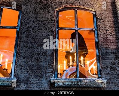 Silhouette de nonne dans la fenêtre avec des bougies religieuses pour Noël Banque D'Images