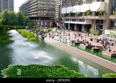 Les gens se détendent sur la terrasse au bord du lac près des fontaines d'eau en été à l'extérieur au Barbican Centre arts Building extérieur à Londres Angleterre KATHY DEWITT Banque D'Images