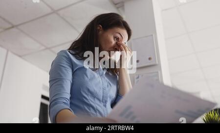 Jeune entrepreneur souffrant de maux de tête au bureau essayant de travailler sur un nouveau projet de développement. Manager professionnel frottant les tempes ayant une migraine douloureuse dans l'espace exécutif. Prise de vue à main levée. Banque D'Images