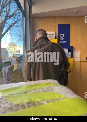 paris, France - 21 février 2023 : vue arrière d'un homme achetant des timbres dans un bureau français de la poste depuis le distributeur automatique. Banque D'Images