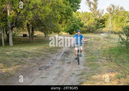 Un homme âgé athlétique monte un vélo pliant dans Whitetail Campground dans la forêt nationale du Nebraska Banque D'Images