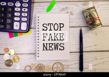 Femme tenant le mégaphone et la plaque avec le texte ARRÊTER LES FAUSSES NOUVELLES sur fond sombre. Banque D'Images