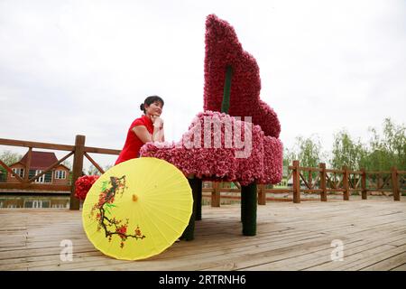 Comté de Luannan - 17 mai 2018 : une dame est assise devant une sculpture de piano dans le parc, comté de Luannan, province du Hebei, Chine Banque D'Images
