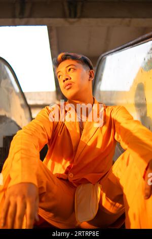 Un homme asiatique en costume jaune est assis sur un ascenseur dans un immeuble dans l'après-midi Banque D'Images