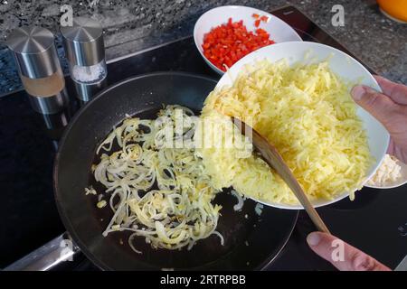 Cuisine souabe, préparation de strudel de pommes de terre copieux, friture des rondelles d'oignon dans la graisse, ajout de pommes de terre râpées et cuites, préparation de la garniture, légumes Banque D'Images