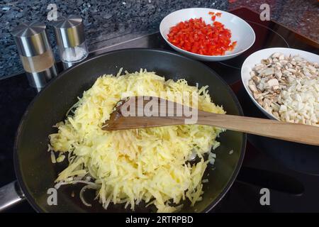 Cuisine souabe, préparer un strudel de pommes de terre copieux, frire des pommes de terre râpées et bouillies, faire la garniture, des légumes, strudel salé avec des légumes Banque D'Images