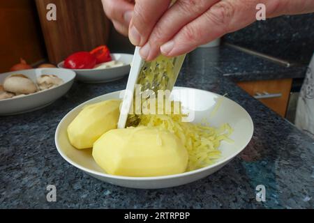 Cuisine souabe, préparation de strudel copieux de pommes de terre, râpage de pommes de terre bouillies et pelées, râpe, trancheuse de légumes, préparation de strudel salé avec des légumes Banque D'Images