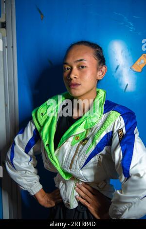 Un homme asiatique gay posant magnifiquement sur un fond bleu la nuit Banque D'Images