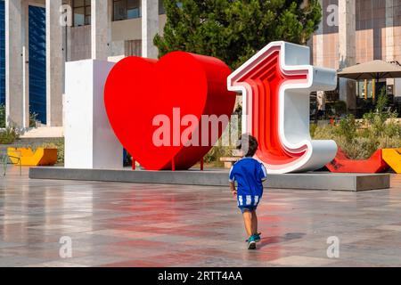 Un enfant dans la sculpture I Love Tirana sur la place Skanderbeg à Tirana a réfléchi. Albanie Banque D'Images