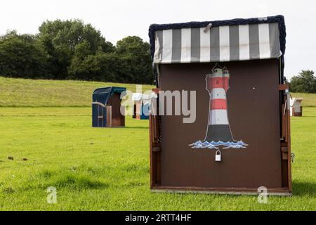 Chaise de plage avec peinture de phare sur une prairie verte à la plage de Cuxhaven, côte de la mer du Nord, Basse-Saxe, Allemagne Banque D'Images