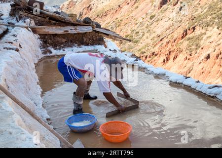 Maras, Pérou, 11 octobre 2015 : Homme travaillant dans un bassin d'évaporation de sel dans les mines de sel de Maras Banque D'Images