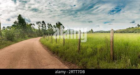 Chemin de terre et barbelés sur l'après-midi d'été dans les montagnes de Minas Gerais, Brésil Banque D'Images