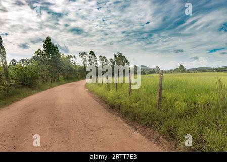 Chemin de terre et barbelés sur l'après-midi d'été dans les montagnes de Minas Gerais, Brésil Banque D'Images