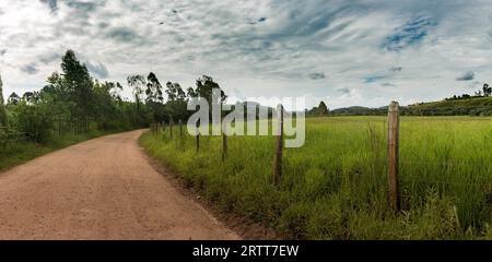 Chemin de terre et barbelés sur l'après-midi d'été dans les montagnes de Minas Gerais, Brésil Banque D'Images