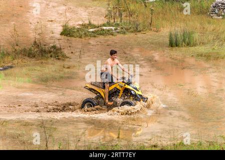 Minas Gerais, Brésil, 27 décembre 2015 : Homme dans la nature sortir de la route sur un rallye quad sur une flaque de boue dans la campagne Banque D'Images