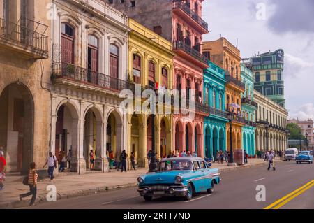 Un taxi oldtimer bleu traverse Habana Vieja devant une façade colorée de bâtiments coloniaux, la Havane, CUBA en décembre 2015 Banque D'Images